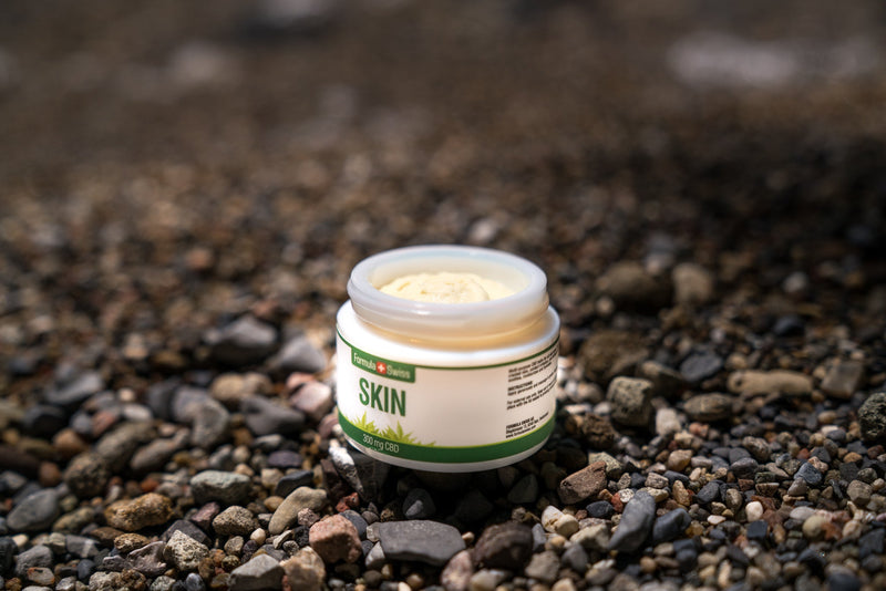 Otvorena posudica balzama Formula Swiss CBD Skin, 300 mg CBD-a, na šljunčanoj plaži