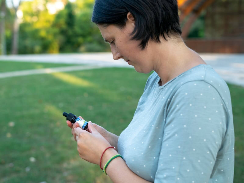 Žena na otvorenom gleda bočicu CBD ulja Formula Swiss u ruci